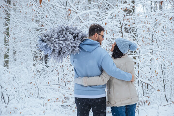 man and woman looking at each other hugging in snowy forest