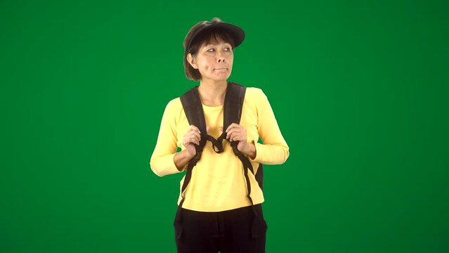 Green screen attractive mature asian woman with backpack and visor enjoying walking outdoors