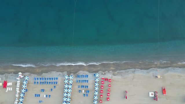 Empty beach with sun loungers and parasols on the sea coast, view from a drone.