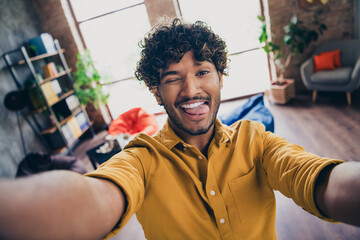 Photo portrait of handsome young guy wear yellow shirt selfie photo stick tongue wink funky stylish...