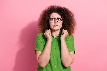 Photo portrait of attractive young woman raise fists nervous look empty space wear trendy green clothes isolated on pink color background