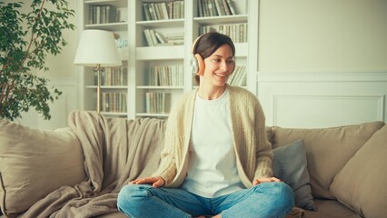 Portrait of young woman relaxing at home and listening music. Girl sitting on sofa. Relaxation,...
