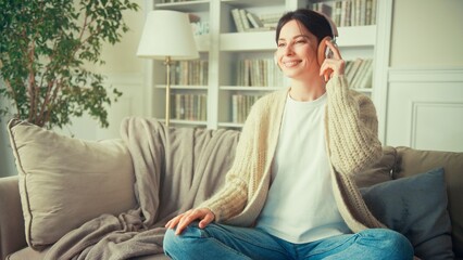 Obraz premium Portrait of young woman relaxing at home and listening music. Girl sitting on sofa. Relaxation, Meditation and Mindfulness