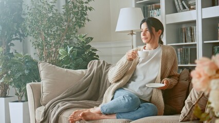 Relaxed woman drinking coffee or herbal tea and feeling carefree and refreshed while relaxing on...