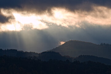 Dramatic evening sky with sun rays and clouds above hills and mountains near to Roznov pod Radhostem, Czech republic. Late Autumn.