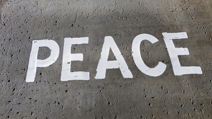 A palavra "PEACE" pintada no chão de concreto com tinta branca. 