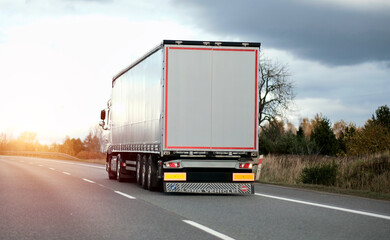 Modern white semi-trailer trucks on the highway driving in the right lane. Commercial vehicle for...