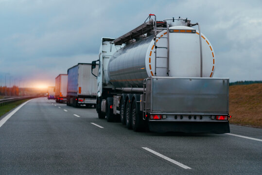 Petrol cargo truck driving on highway hauling oil products. Fuel delivery transportation. Aviation fuel transportation. Compressed gas carrier truck rear view on a highway. Dairy products carrier.