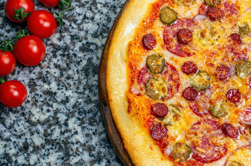 Ready-made pizza with sausage, blue onions and cucumbers. Cherry tomatoes
