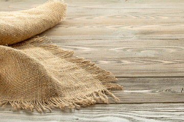 Stack of burlap napkins with fringe on wooden table close-up, rustic style