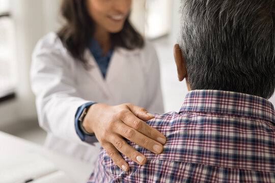 Hand of friendly young geriatric doctor touching shoulder of senior patient with care, empathy, giving sick older man consultation for treatment, checkup, explaining diagnosis