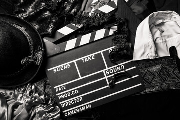 movie clapperboard against the background of clothes and a hat, black and white photo