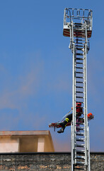 firefighter on long ladder truck while transporting the injured person on a stretcher to save him...