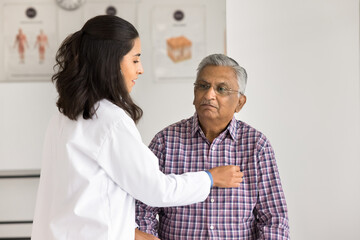 Senior Indian patient visiting medical practitioner woman for heart work checkup. Young Latin...