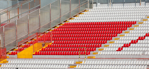 empty red and white seats in the stadium stands without people before the sporting event