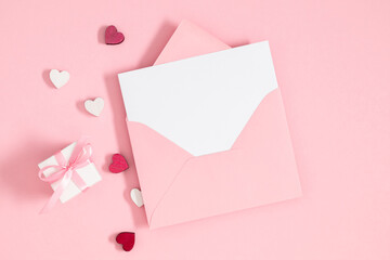 Creative minimal Valentines day concept. Envelope, valentines, hearts confetti on pastel pink background. Flat lay, top view, copy space