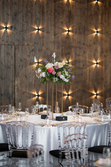 Centerpiece made of green leaves and fresh flowers stands on the dinner table. Wedding day.