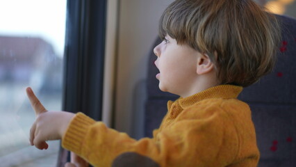 Close-up of a young caucasian boy, eyes wide with wonder, as he gazes intently out of a train...