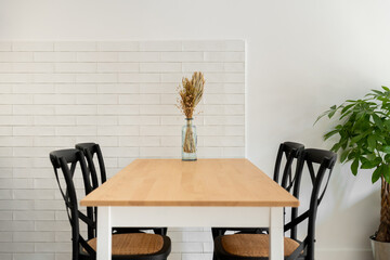 Wooden table with chairs and dry flowers bunch in dining room