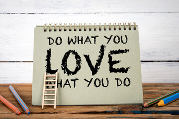 Do what you love, love what you do. Green notepad on wooden texture table and white background