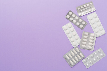Pills in blister packaging on color background, top view
