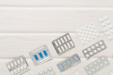 Pills in blister packaging on wooden background, top view