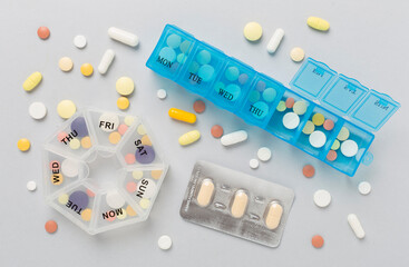 Daily pill organizer with medications on color background, top view