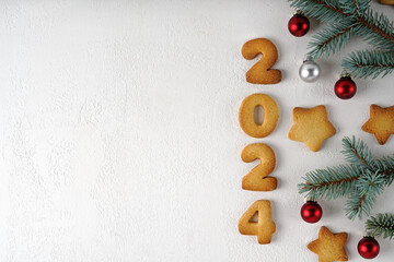 Christmas and New Year composition of cookies numbers 2024 on concrete background and decorated with pine twig and christmas toys. Big copy space