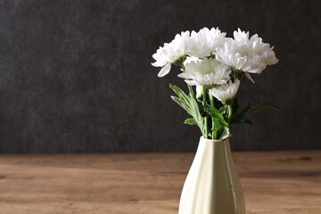 グレーの壁背景の花瓶に活けた白菊