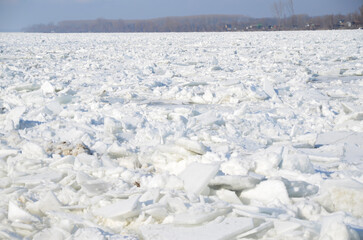 Fototapeta na wymiar Thick white snow-covered ice floes float along a wide river danube.