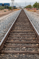 railroad tracks going into horizon in rural setting surrounded by rocks and pebbles