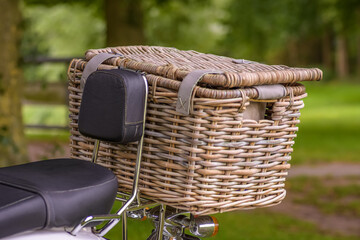 Picnic basket on the back of a scooter in a wooded area. A nice way to eat outside