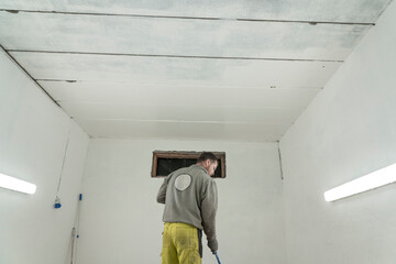 Skilled Worker in Branded Attire Transforms Spacious Room or Garage with Expert Painting.