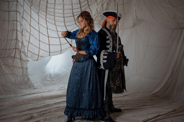 A lady and a pirate in an antique doublet and hat, a couple in pirate costumes. sails on the...