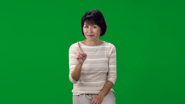 Green screen attractive woman sitting looking at camera smiling making humorous hand gestures