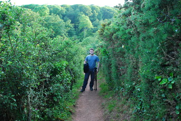 Fototapeta premium Man is standing on a footpath in a lush green environment 