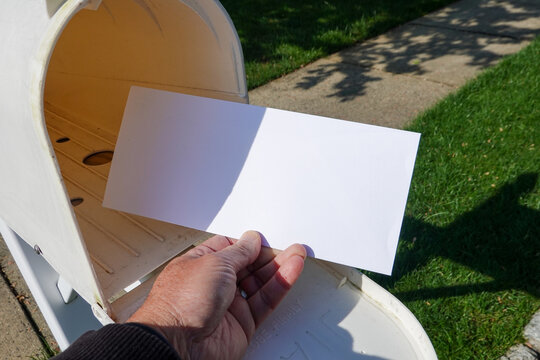A male hand taking a blank white envelope out of a mailbox
