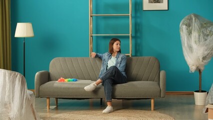 Close up shot of apartment living room. Woman sitting resting on the sofa after cleaning it in the new apartment room.