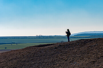 A hiker taking pictures with a phone in a barren winter landscape