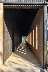 A Long External Corridor at a Resort in Chile with Sunlight Penetrating to a View at the end of the Walkway