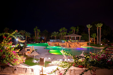 Swimming pool and palm trees at night in Hammamet, Tunisia
