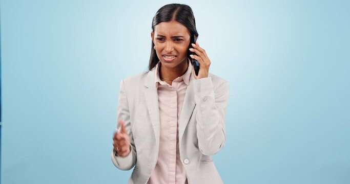 Phone call, argument and business woman in a studio with moody, upset and angry expression. Annoyed, technology and professional Indian person on mobile conversation with cellphone by blue background
