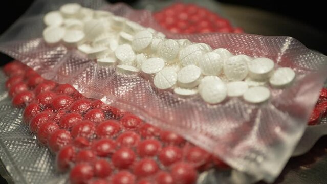 Powder drugs pressed in pills shape and packaged in to vacuum bags for transportation. Stash of Oxy, Meth, Fentanyl or synthetic opioid drugs, seized by police or security, illegal drugs trafficking.