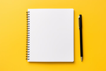 Stock photo of a white tablet with a black notebook and a white pen on a yellow background