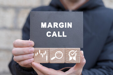 Man holding wooden cubes with icons and black sticky note with text: MARGIN CALL. Trading loss...