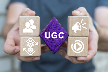 Businessman holding colorful blocks sees abbreviation: UGC. UGC User generated content concept. Online marketing. Customer create content on social media.