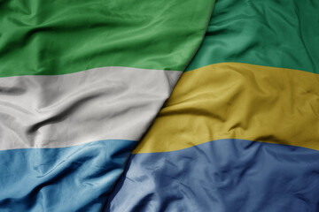 big waving national colorful flag of sierra leone and national flag of gabon .