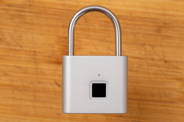 closed light gray padlock with fingerprint opening.  woode color background to cut out.