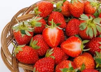 Ripe strawberries in wicker tray on white background