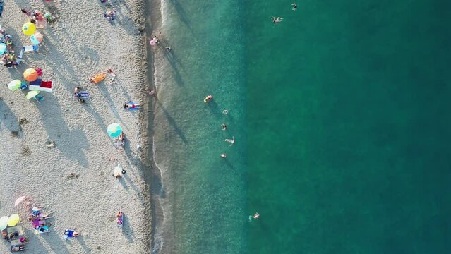Beach on the sea coast with vacationers, view from a drone.